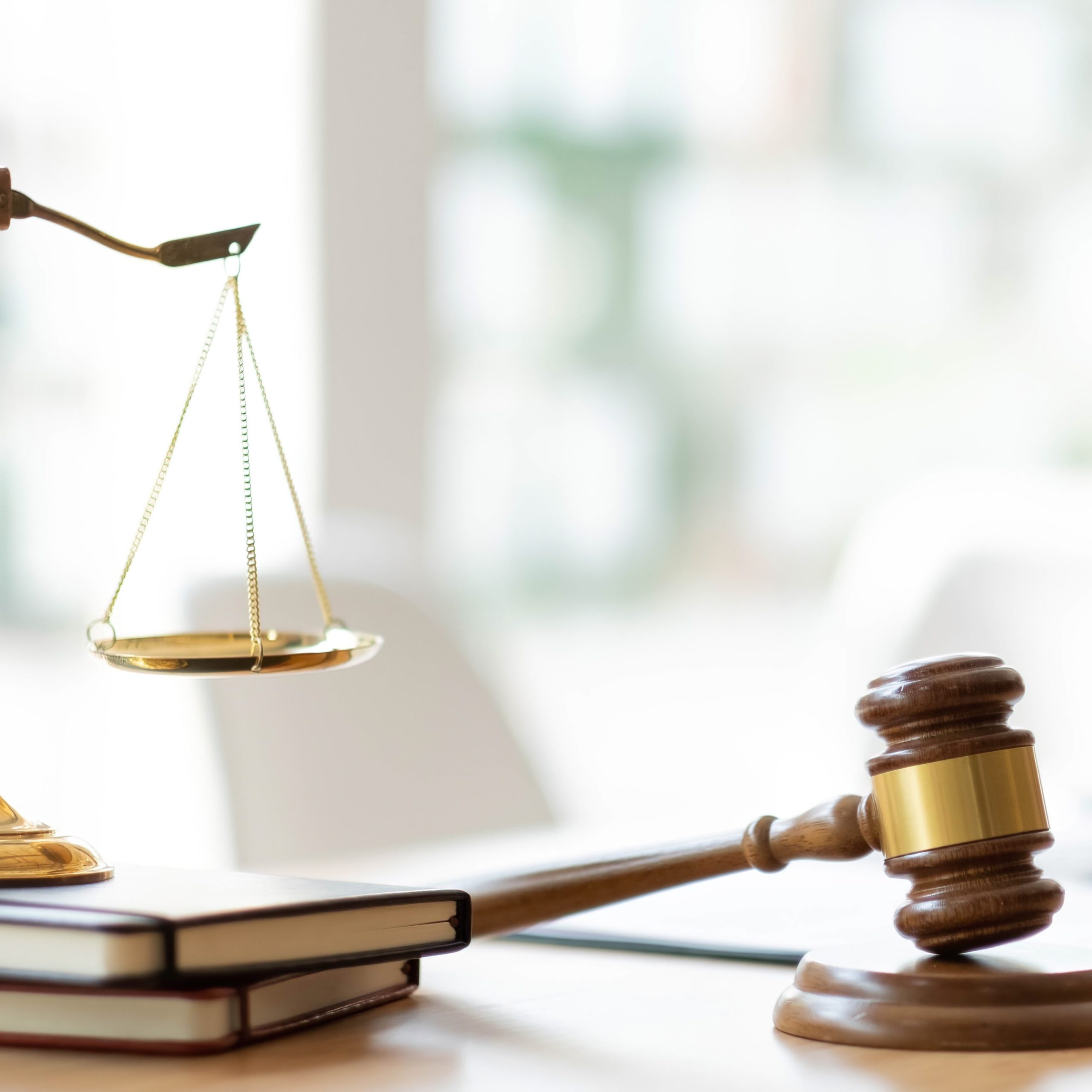 Balance de la justice et marteau de juge posés sur un bureau, symbolisant le conseil juridique, la défense des droits et les procédures judiciaires.