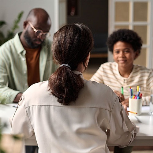 Entretien entre une famille et un professionnel autour d’une table, dans le cadre d’un accompagnement en droit de la famille ou d’une médiation familiale.